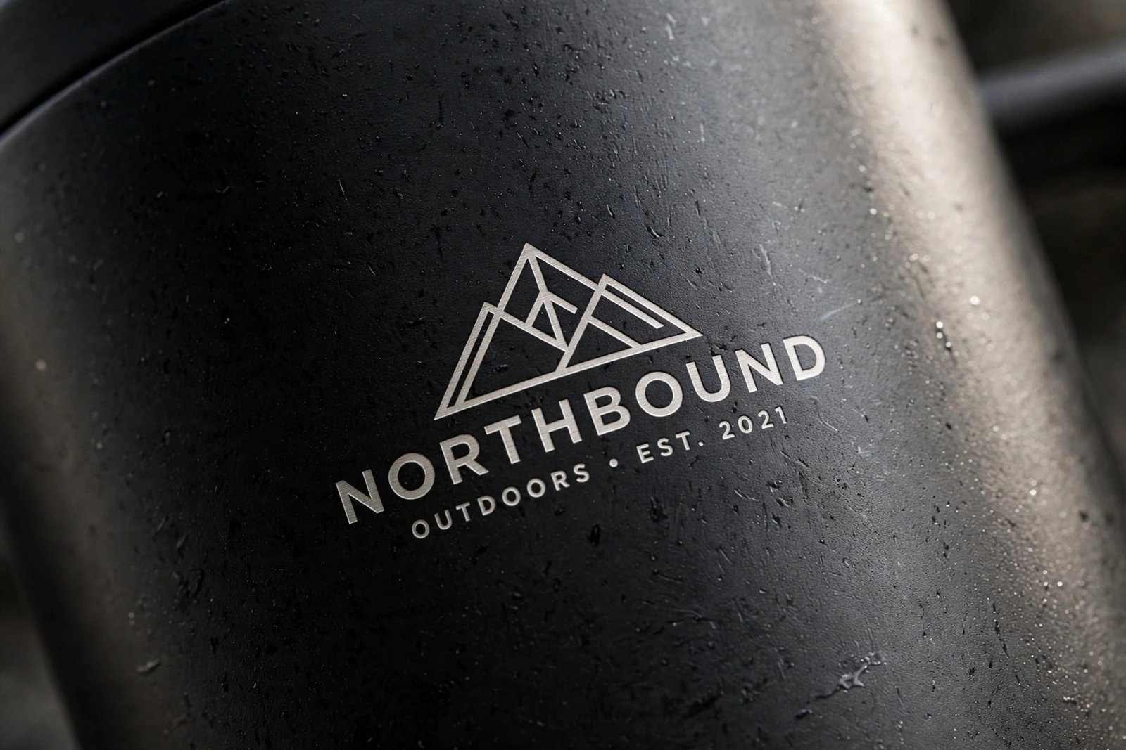 Close up of a laser engraved logo on a matte black stainless steel travel mug